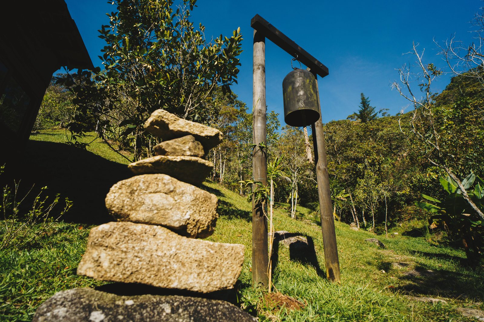 Una campana colgando junto a un cairn de piedras en las montañas