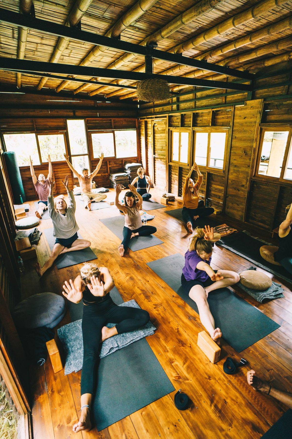 Clase de Hatha yoga vista desde arriba, brazos hacia el cielo