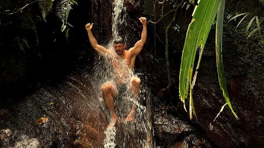 Huésped refrescándose bajo una cascada