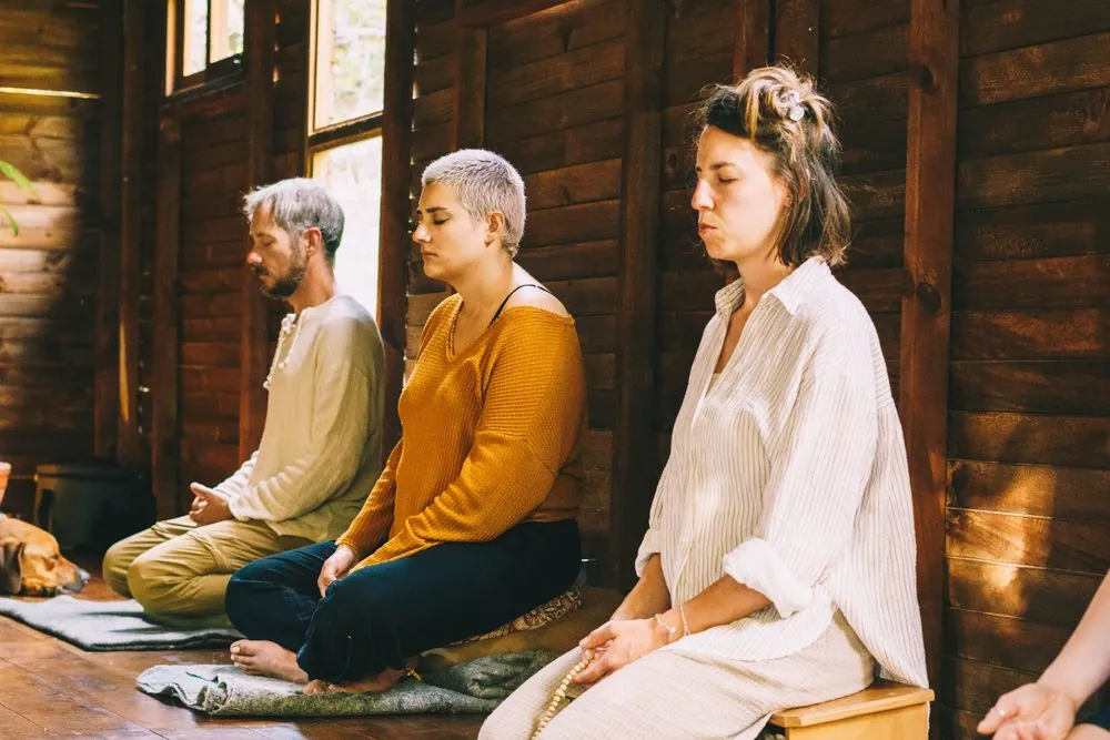 Tres huéspedes en meditación sentada en el salón
